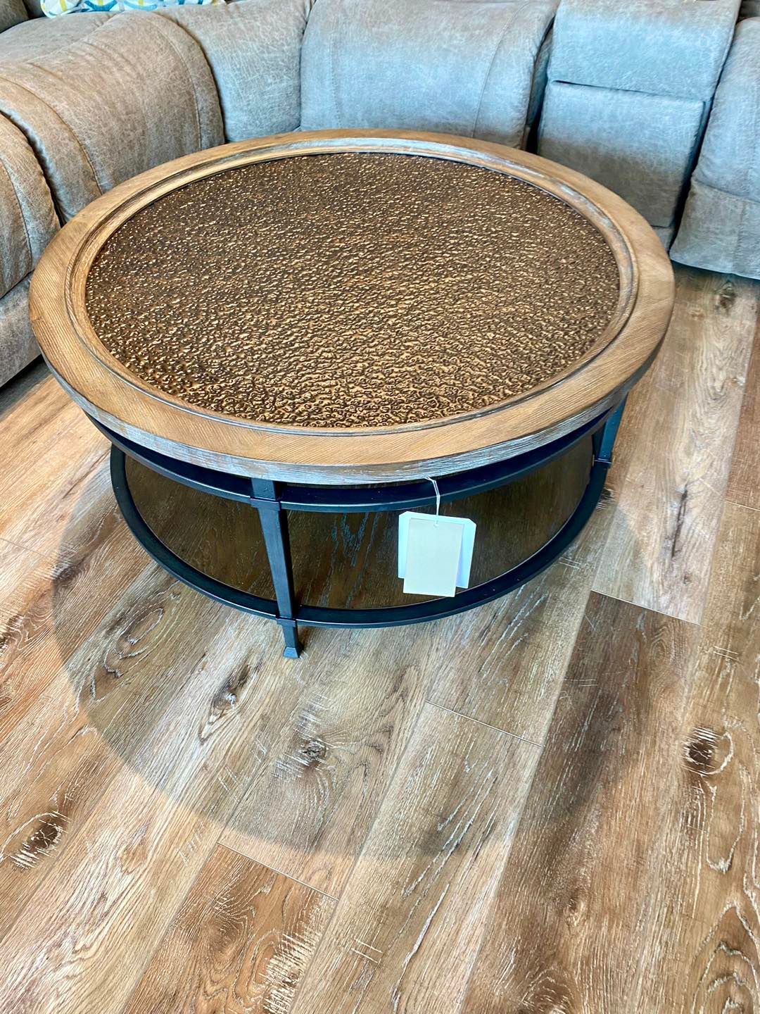 A round coffee table is sitting on a wooden floor next to a couch.