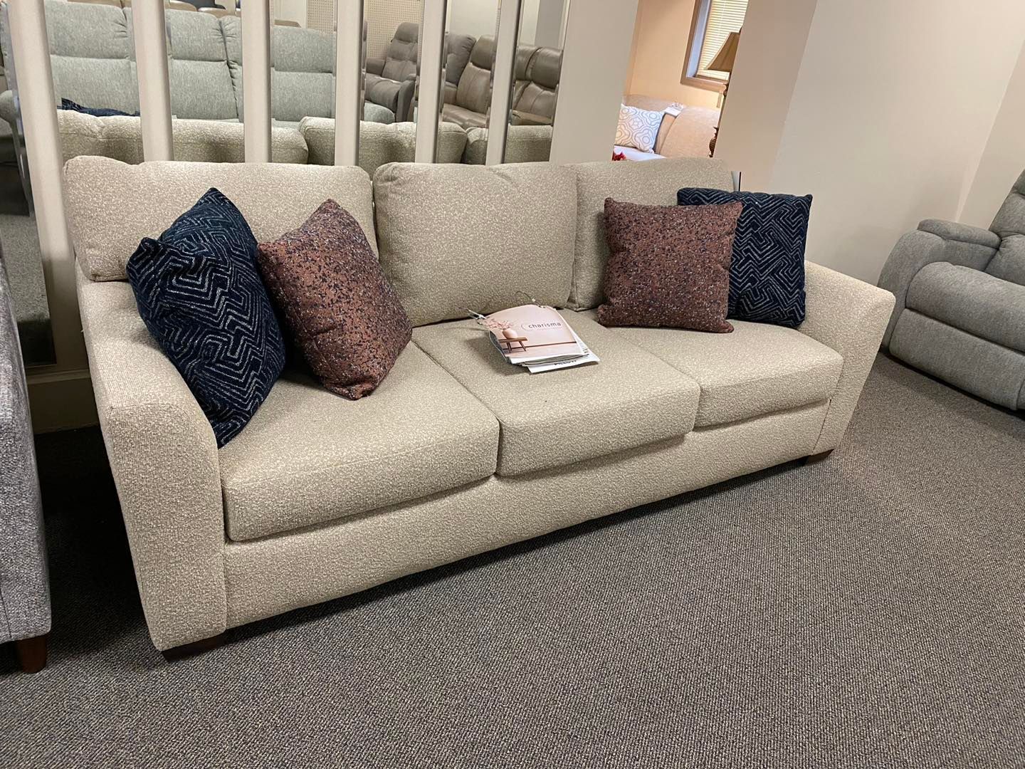 A couch with pillows on it is sitting on a carpet in a living room.