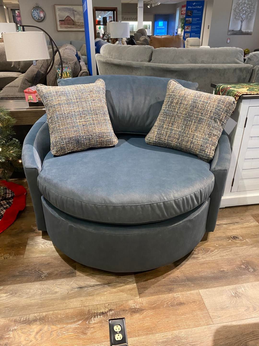 A round chair with two pillows on it is sitting on a wooden floor in a living room.