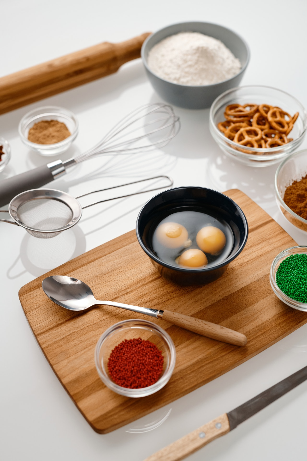 A wooden cutting board topped with bowls of ingredients and a bowl of eggs.