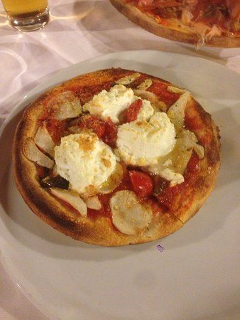 una pizza con pomodoro e formaggio su un piatto bianco.