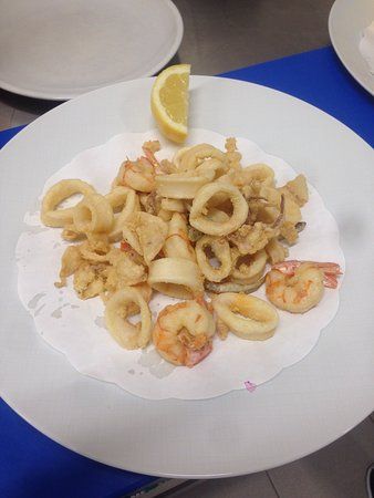 un piatto bianco condito con frutti di mare fritti e una fetta di limone.