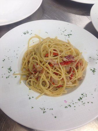 un piatto bianco condito con spaghetti e verdure su un tavolo.