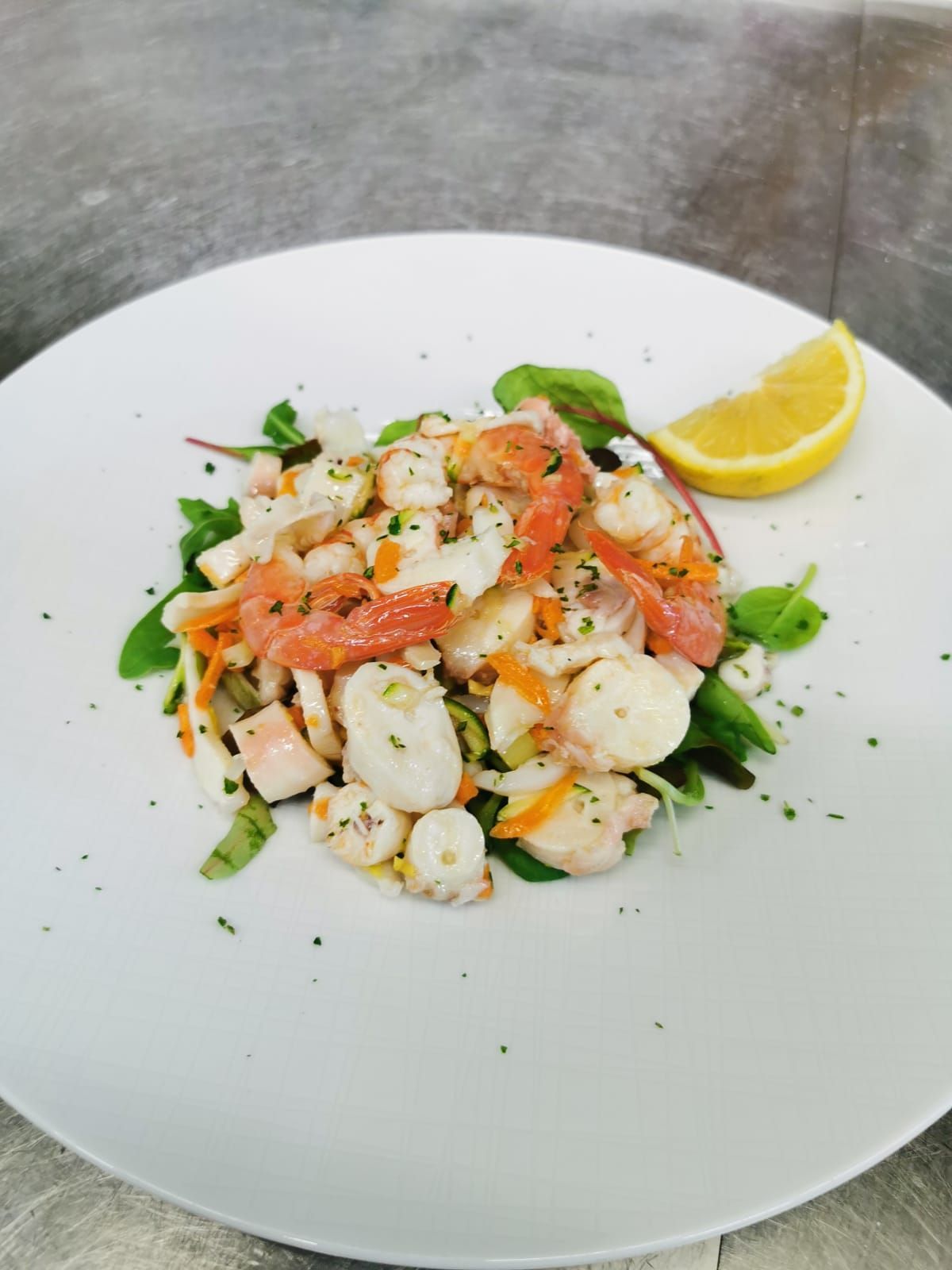 un piatto bianco condito con insalata e una fetta di limone