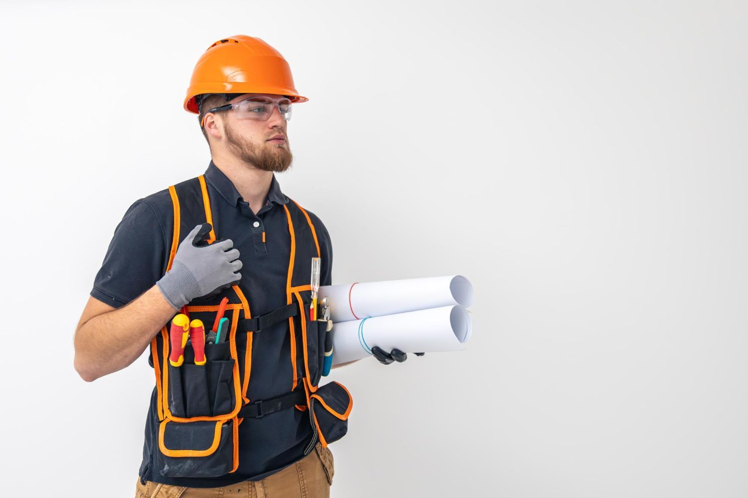 A man wearing a hard hat and safety vest is holding a blueprint.