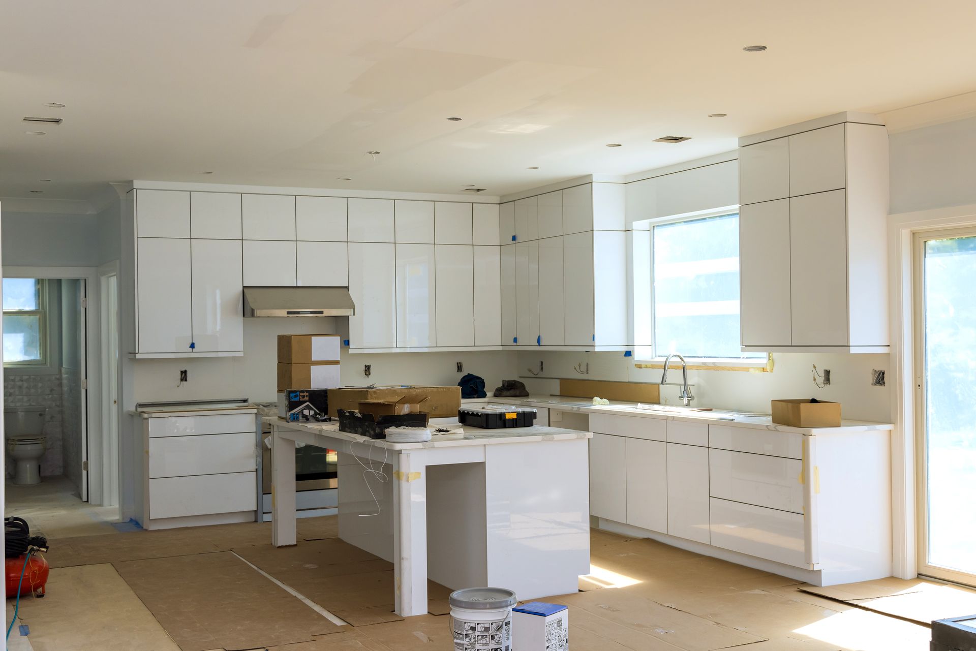 A kitchen under construction with white cabinets and a large island
