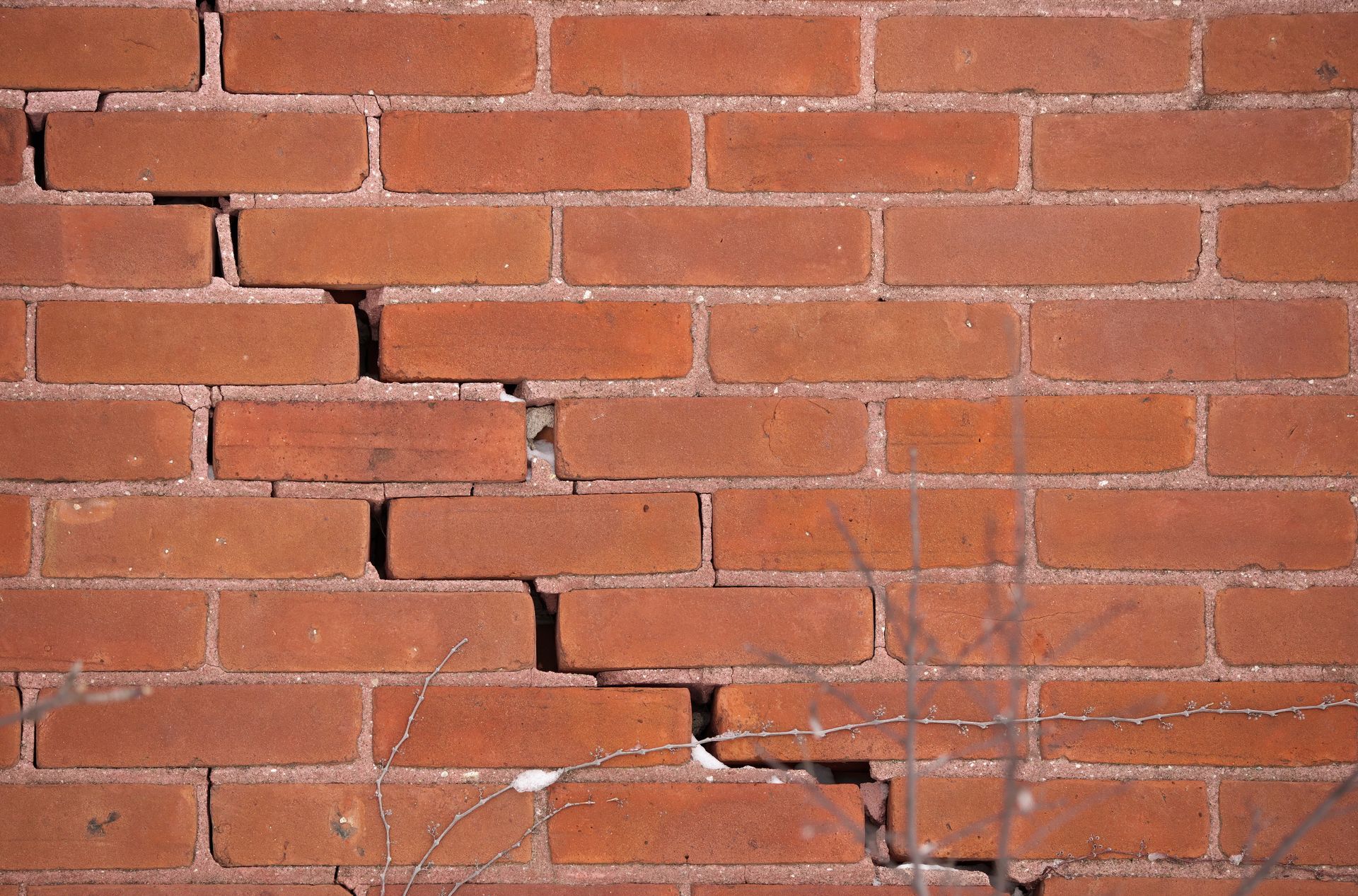 Cracked red brick wall with diagonal fissure.