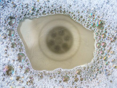 A sink drain filled with soapy water and bubbles.