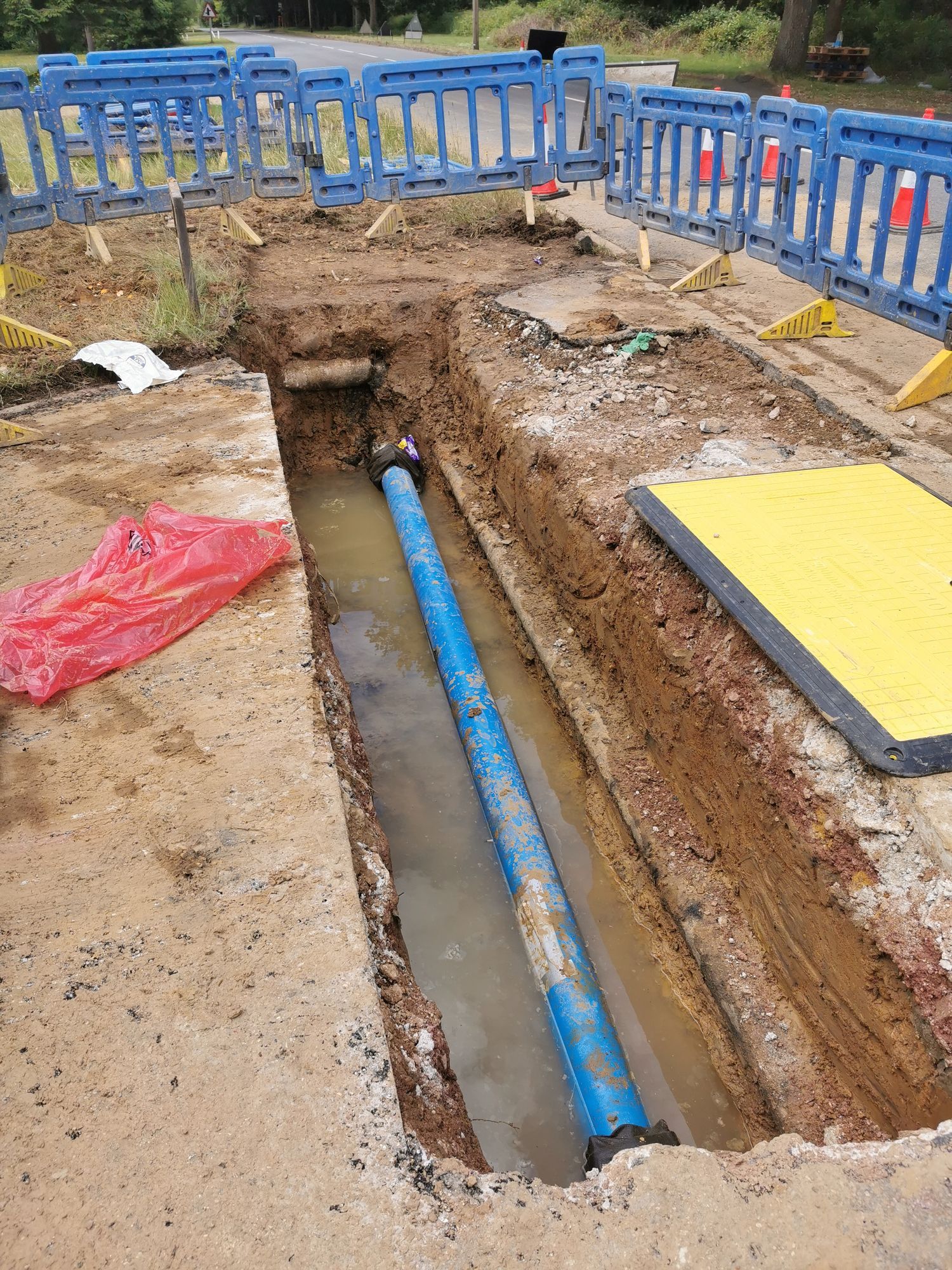 A blue pipe is being installed in a hole in the ground.