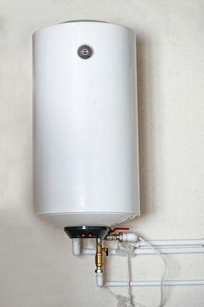A white water heater is hanging on a white wall.