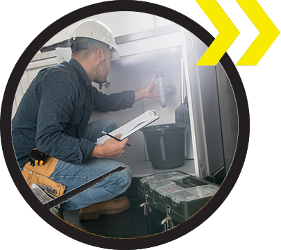 An emergency plumber wearing a white helmet, fixing a problem with the sink in the kitchen. An emergency plumber wearing a white helmet, fixing a problem with the sink in the kitchen.