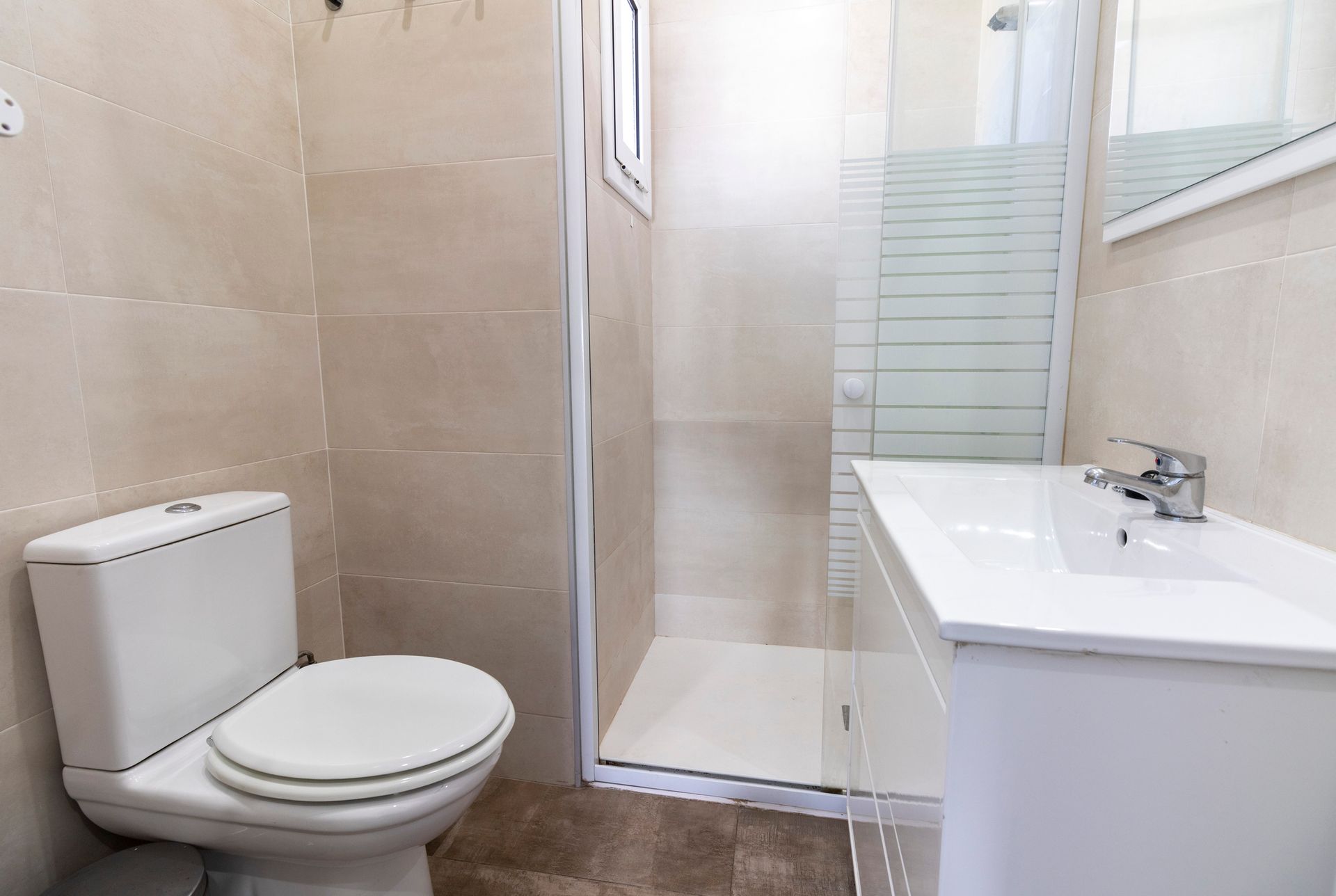 A bathroom with a toilet , sink and shower.