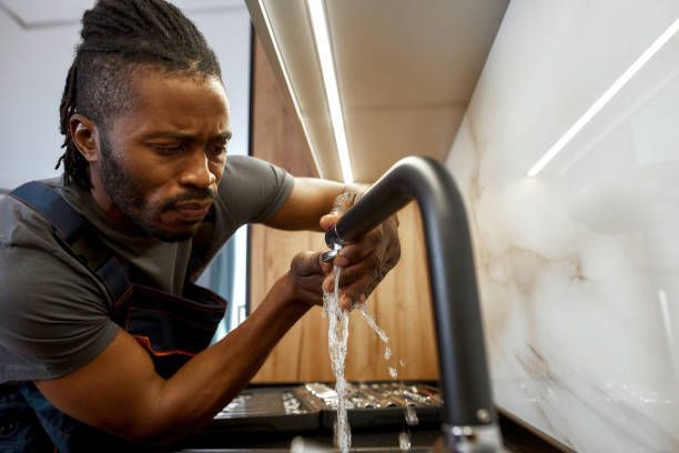 A man is fixing a faucet in a kitchen.