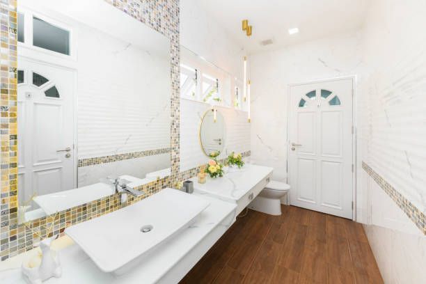 A bathroom with two sinks , a toilet and a mirror.