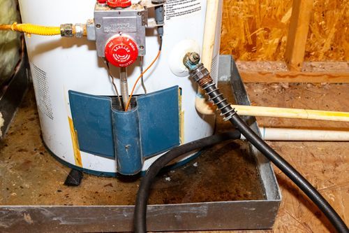 A water heater is sitting on the floor next to a hose.
