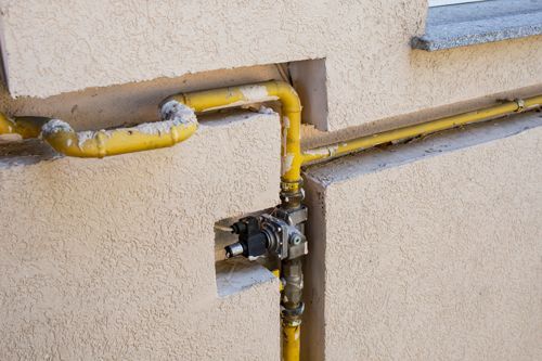 A close up of a gas pipe on the side of a building.