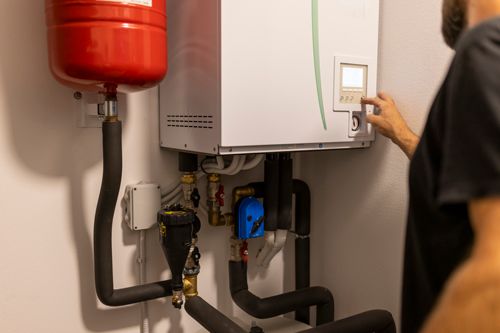 A man is working on a heating system in a room.