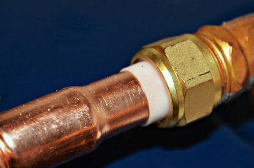 A close up of a copper pipe with a brass fitting.