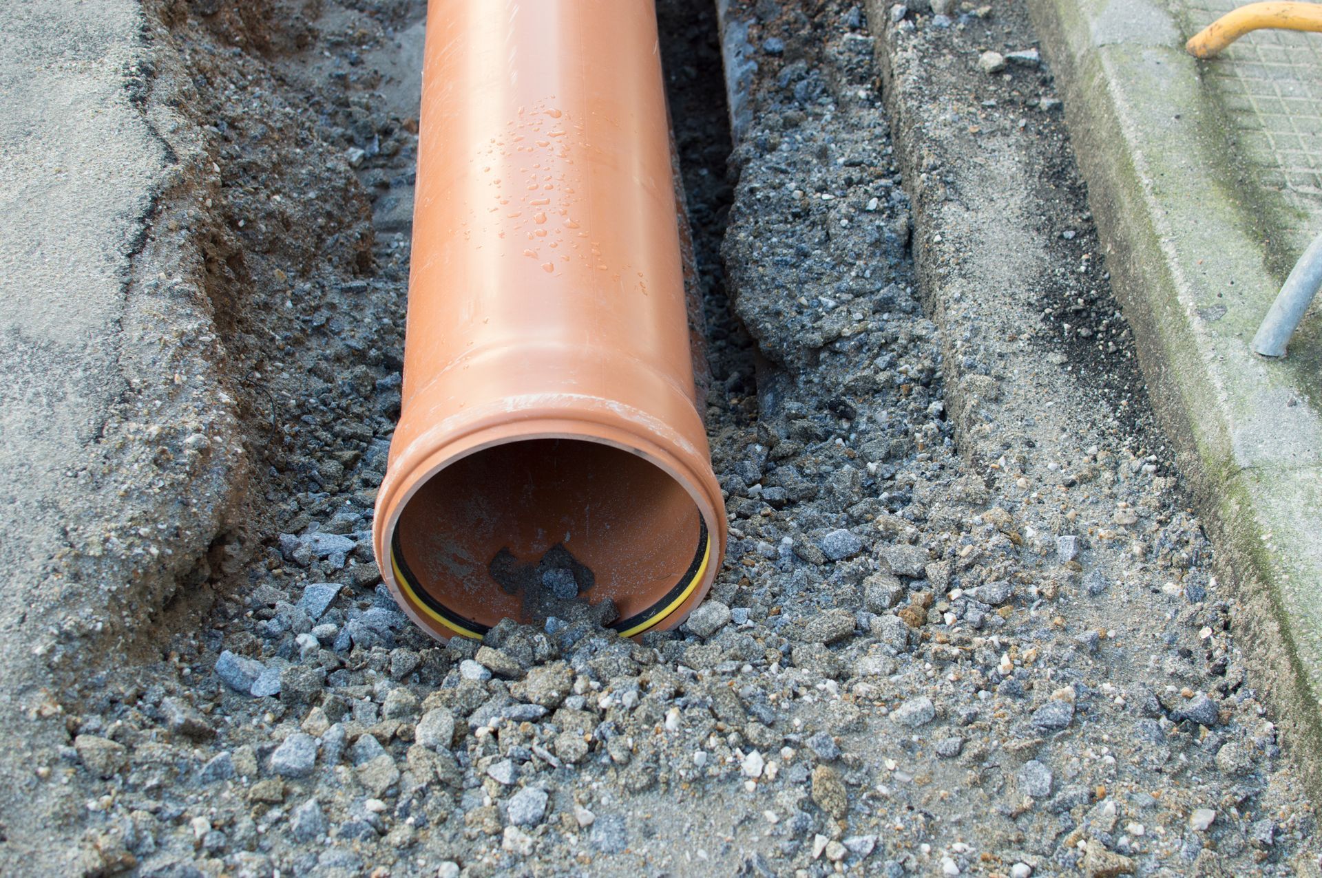 A brown pipe is laying in the dirt on the ground