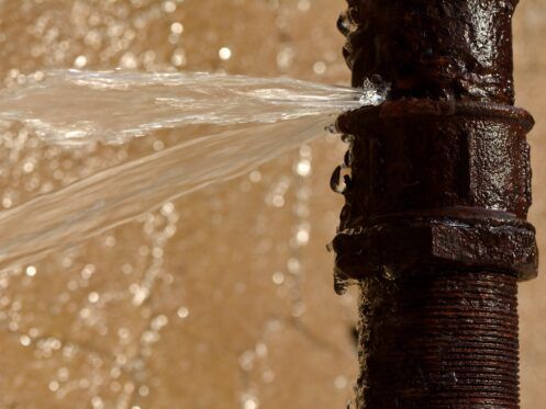 A close up of a rusty pipe with water coming out of it.