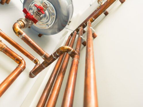 A row of copper pipes connected to a water heater.