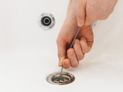 A person is using a drain cleaner to clean a sink drain.