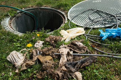 A manhole cover is sitting in the grass next to a septic tank.
