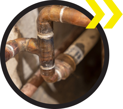 A close up of copper pipes with a yellow arrow pointing to the right