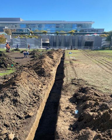 A large building is behind a large pile of dirt.