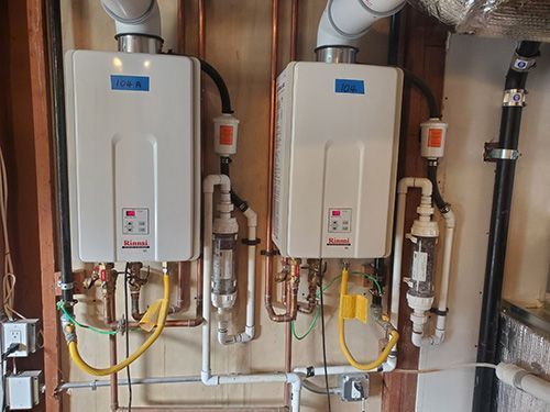 Two water heaters are hanging on a wall next to each other.