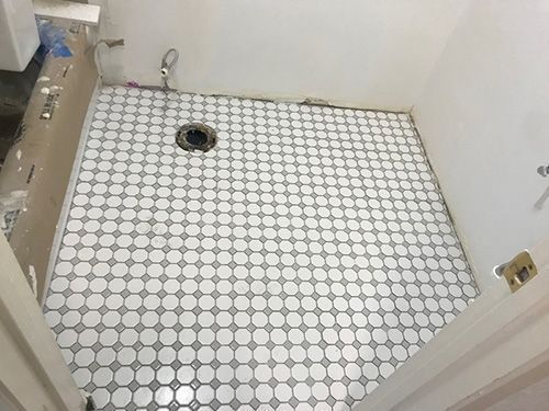 A bathroom with a tiled floor and a toilet.