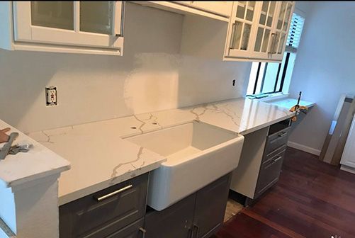 A kitchen with white cabinets and a white sink.