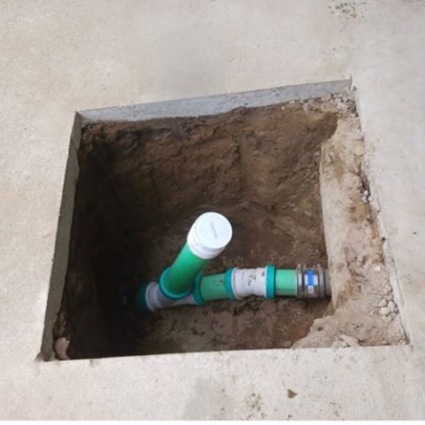 A hole in the ground with green pipes in it