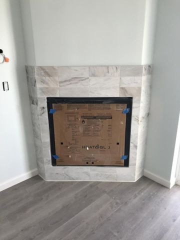 A fireplace is being built in a corner of a room.