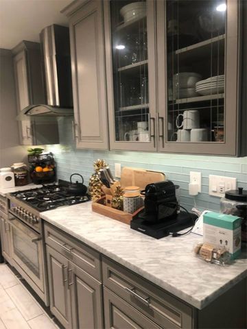 A kitchen with gray cabinets and stainless steel appliances.