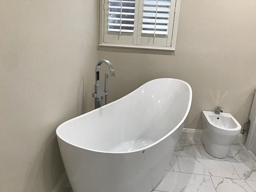 A bathroom with a bathtub , bidet and window.