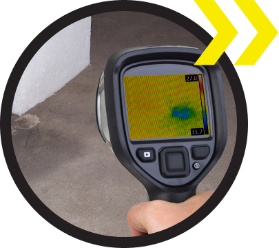 A person is holding a thermal camera that shows a green spot