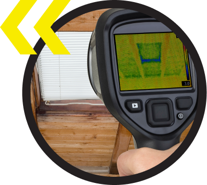A person is holding a thermal camera in front of a window