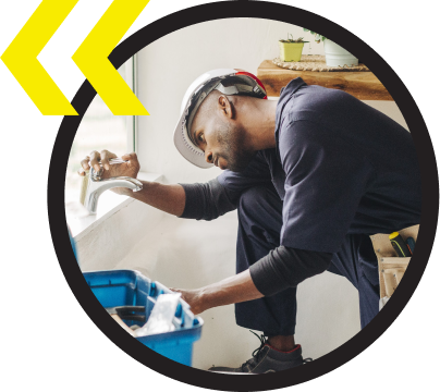 A man wearing a hard hat is working on a sink