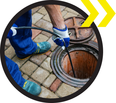 A man is cleaning a manhole cover with a hose.
