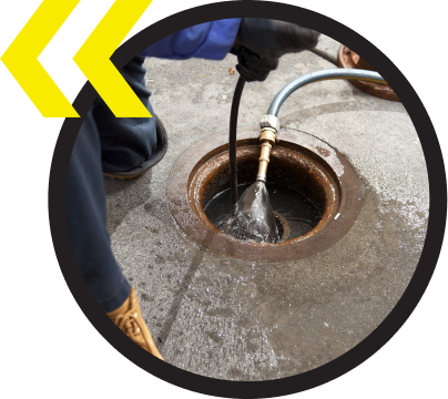 A person is cleaning a manhole with a hose