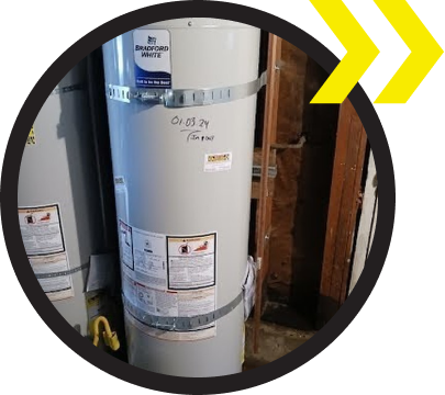 A water heater is sitting in the corner of a room. A water heater is sitting in the corner of a room.
