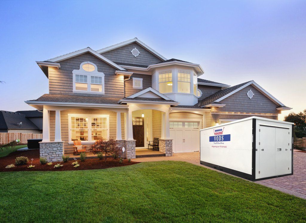 Residential home with VODS portable storage unit in driveway with evening lights.