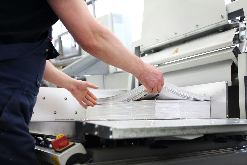 A person is cutting a stack of papers on a machine.