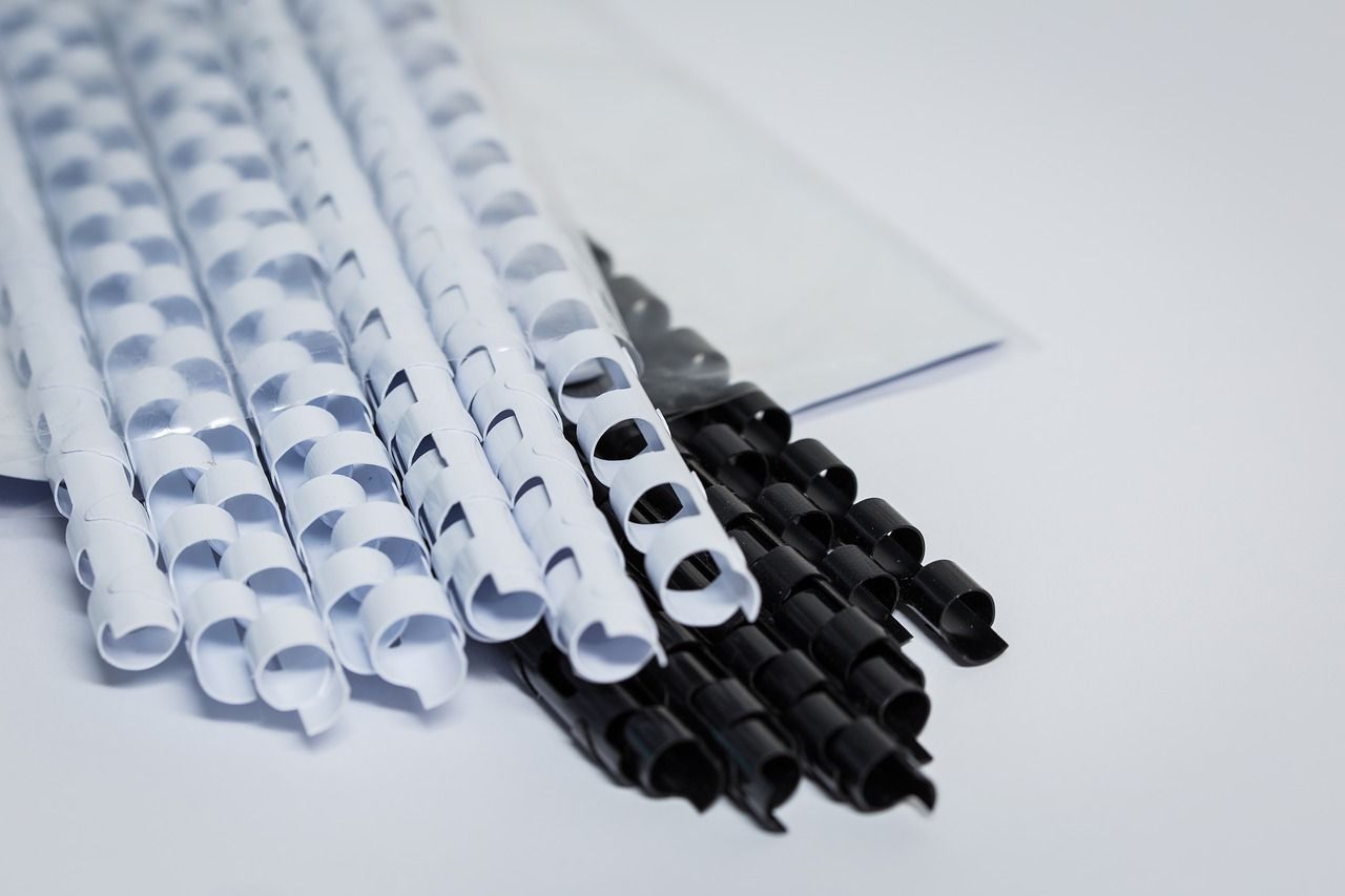 A bunch of black and white plastic binding rings on a white surface.