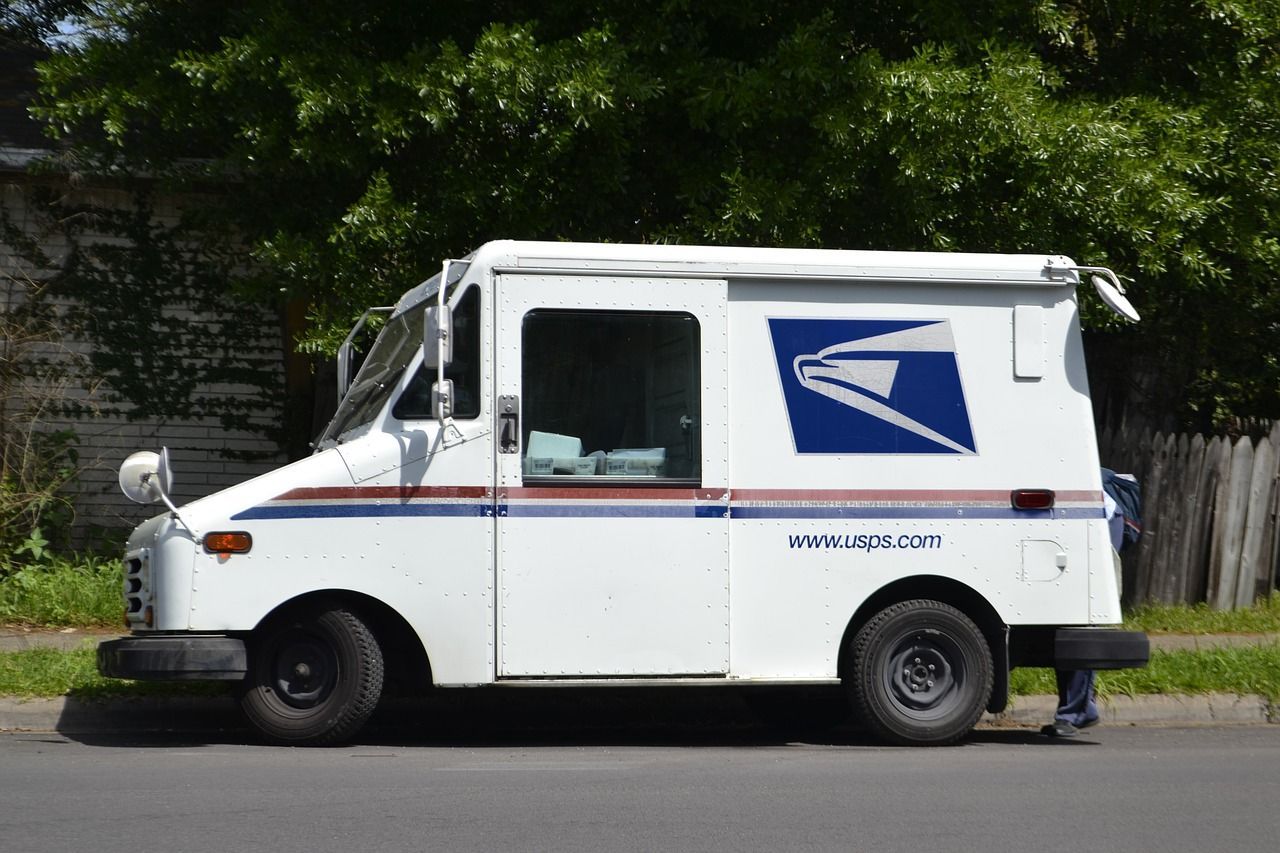 A white mail truck is parked on the side of the road