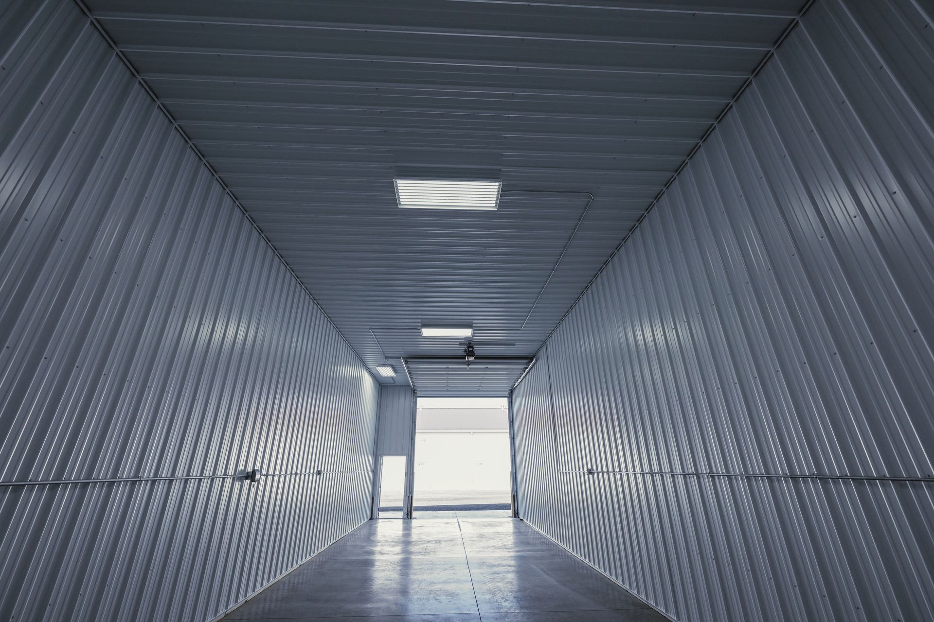 A long hallway with a lot of white walls and a light at the end.