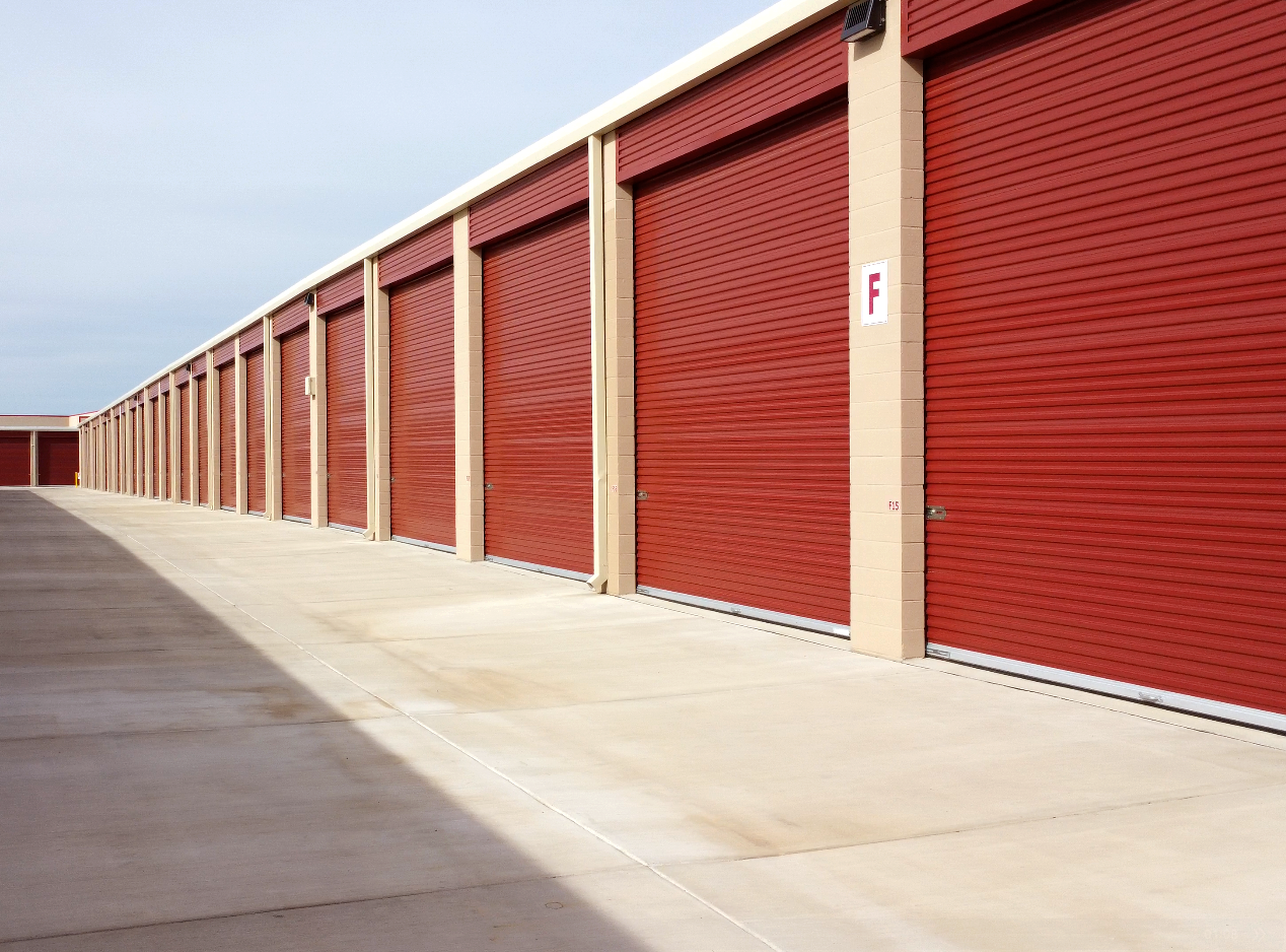 Two rvs are parked in a garage with a blue sky in the background