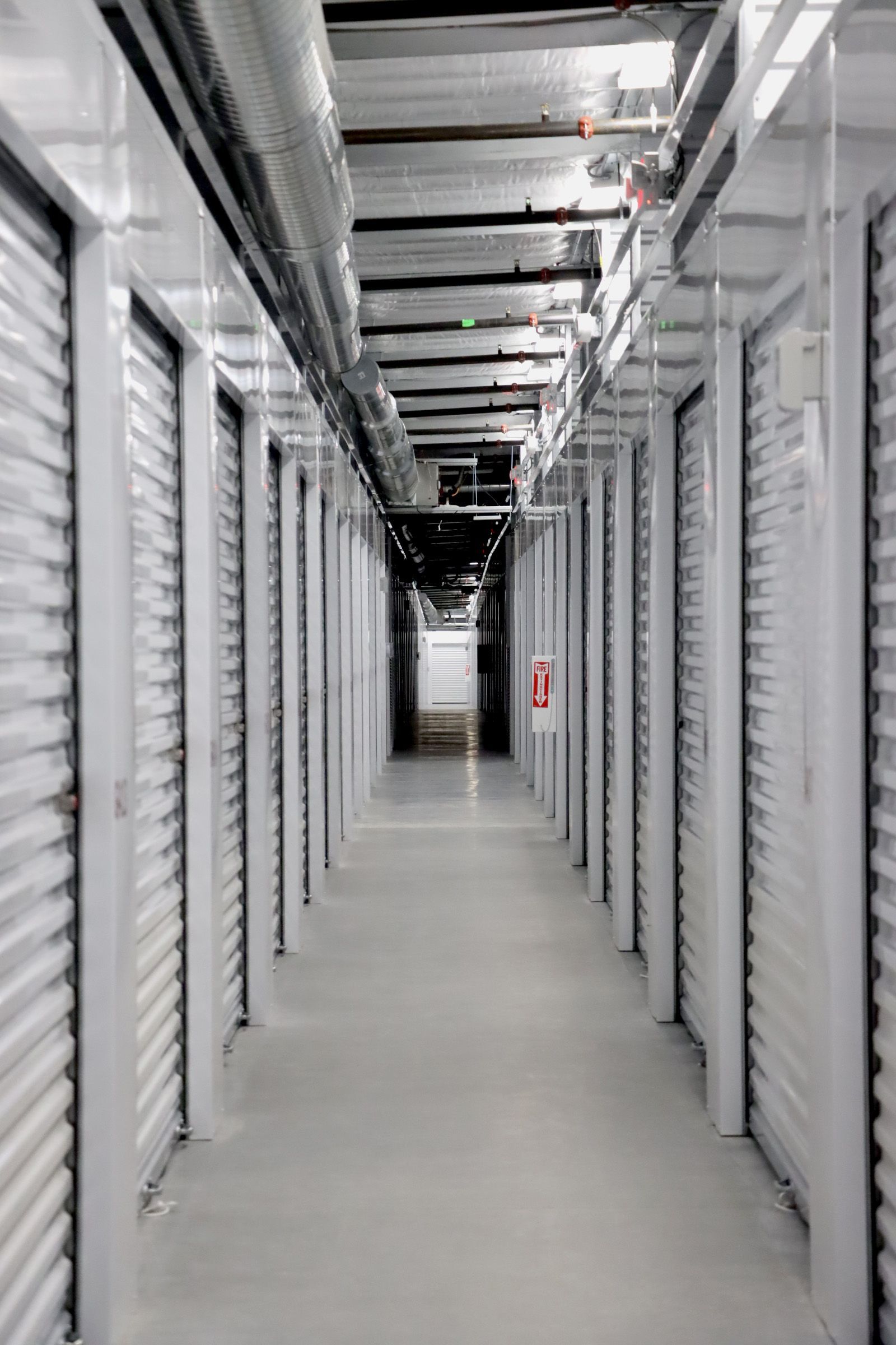 A long hallway with a lot of white walls and a light at the end.