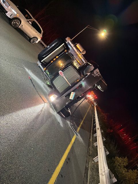 Truck on its side on a road at night, near a street light; white car nearby.